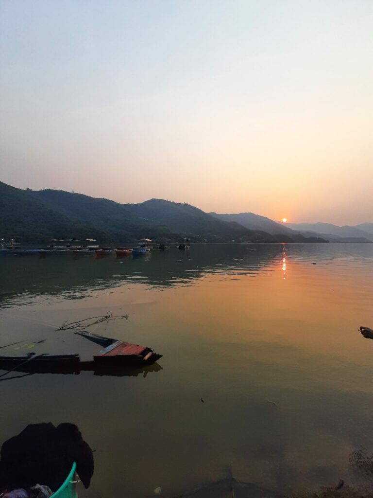 Sunset over mountains and calm water with boats